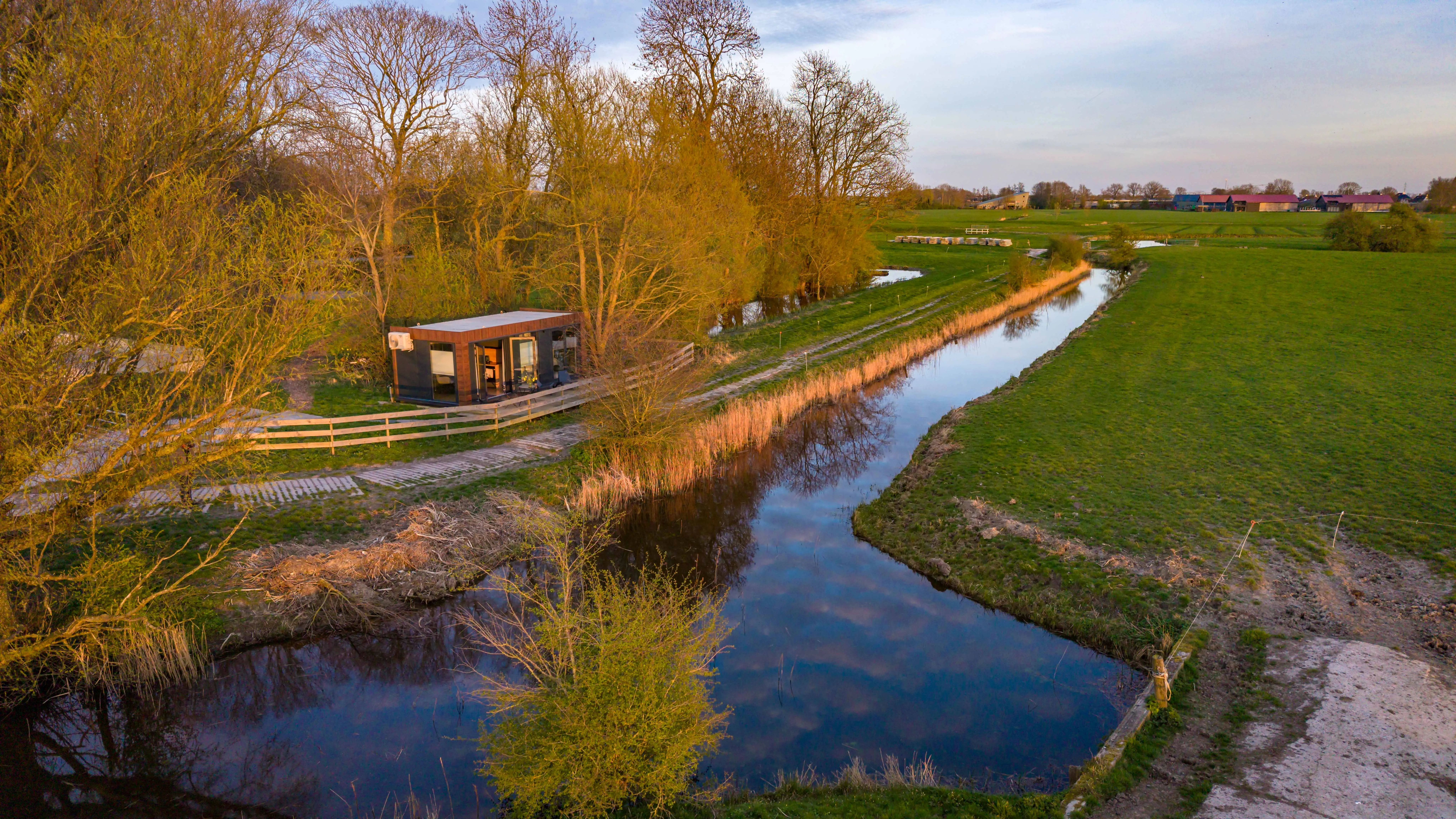 De vaart slingert door de weilanden langs het erf