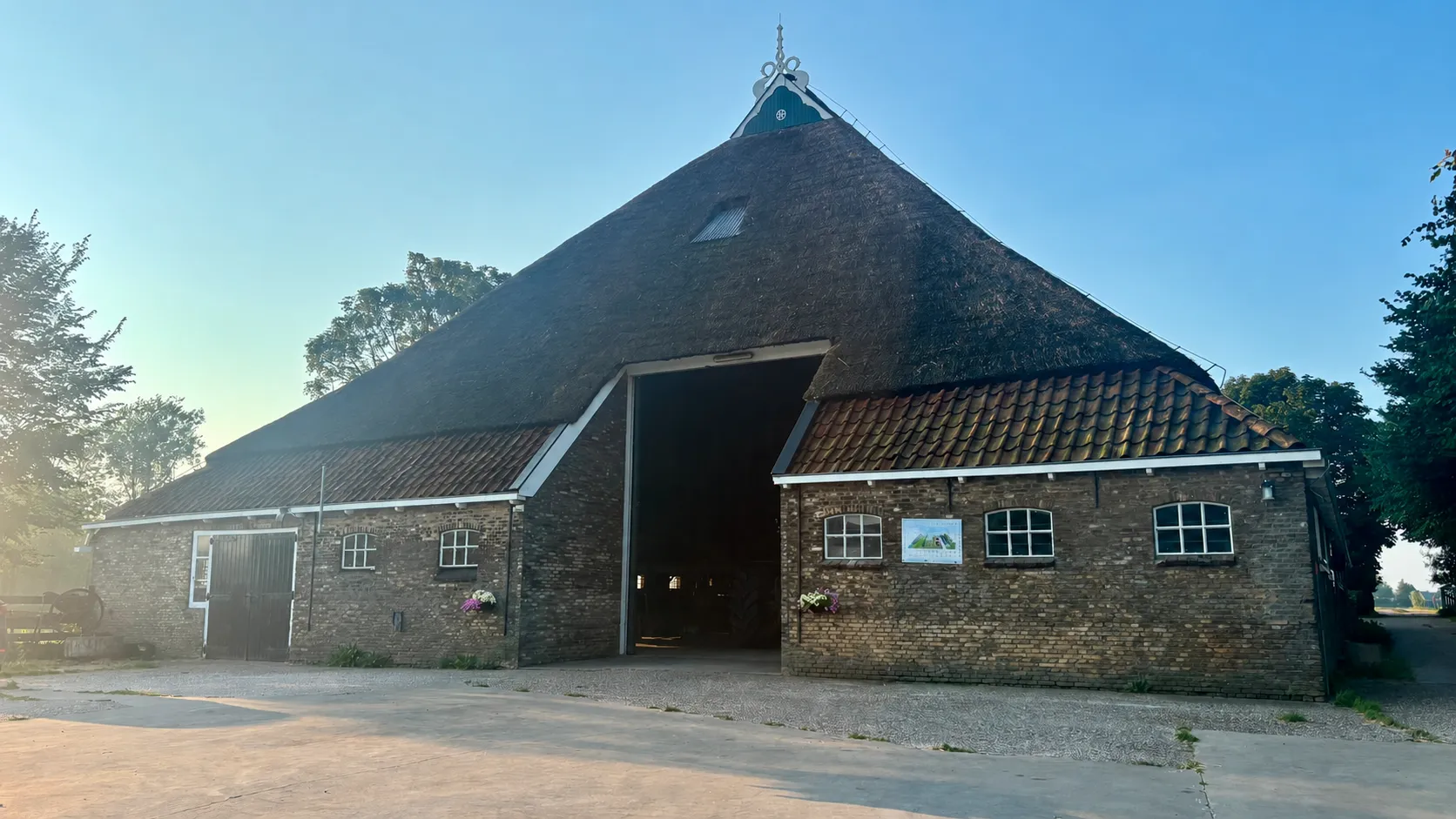 De rietgedekte schuur met open schuurdeuren in de ochtendzon