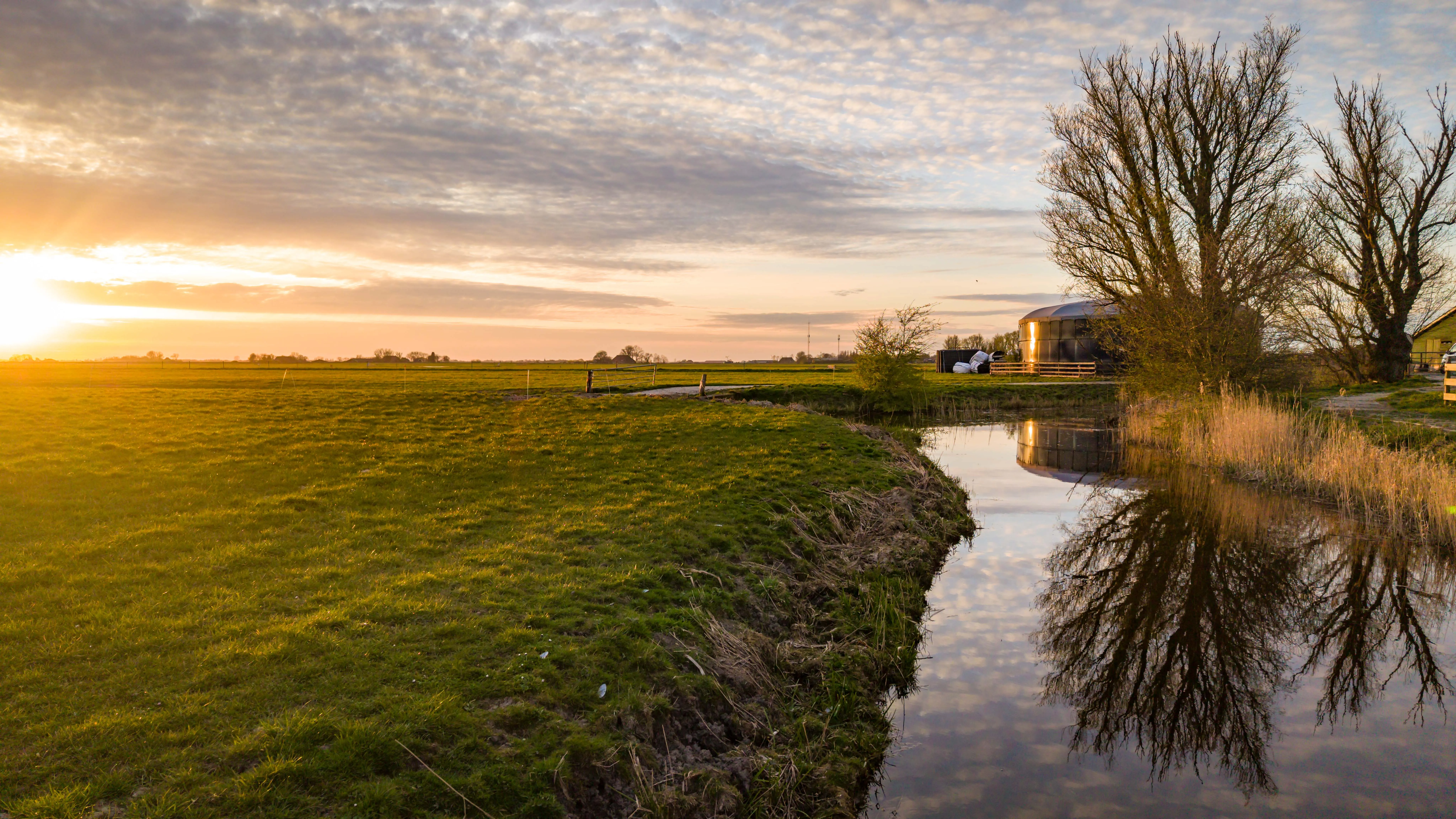 Zonsondergang boven de weilanden en de vaart